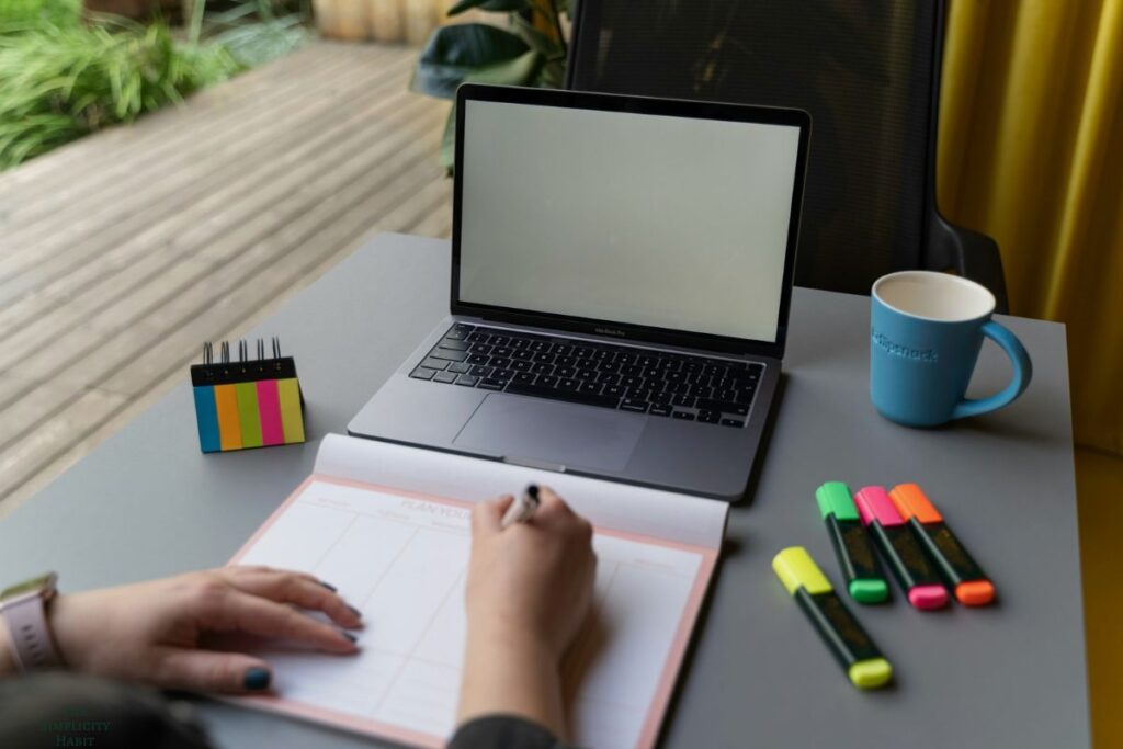 writing in a calendar with a laptop nearby