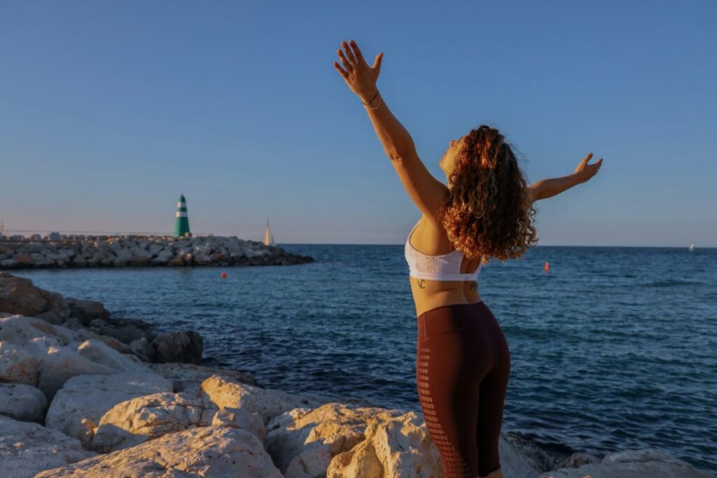 woman with arms raised at the beach